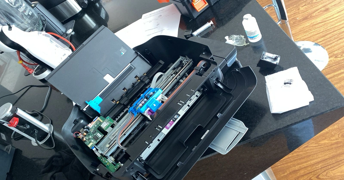 Técnico realizando mantenimiento interno a impresora Epson con cabezal expuesto y sistema de tinta continua
